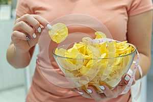 A plate of potato chips and a centimeter tape in the girl`s hands. Junk food. The concept of struggle against excess weight.