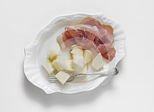 Plate with prosciutto and melon on a light background, top view. Delicious appetizer, tapas