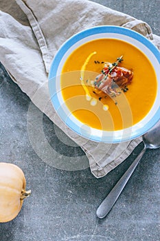 A plate of pumpkin soup with a jamon, garlic