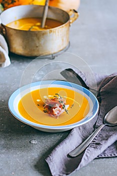 A plate of pumpkin soup with a jamon, garlic, thyme and cream