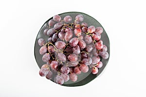 Plate with purple grapes and white background