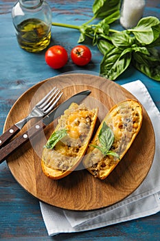 Plate with quinoa stuffed zucchini boats on wooden table