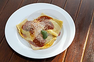 Plate with ravioli grandi on wooden table