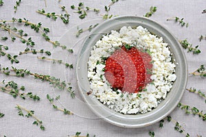 Plate of red caviar with cheese and fresh sprigs of thyme