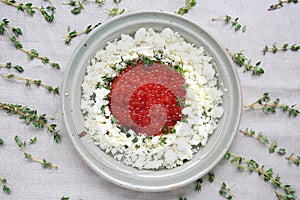 Plate of red caviar with cheese and fresh sprigs of thyme