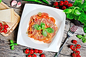 Plate with red heart ravioli with cherry tomato, mozzarella, parmesan and basil on table