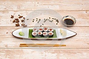 Plate of red tuna maki with white rice with Japanese vinegar with star anise, pumpkin seeds, chopsticks and soy sauce