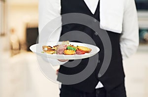Plate, restaurant server and hand with food for luxury fine dining, nutrition and service in night. Waiter man