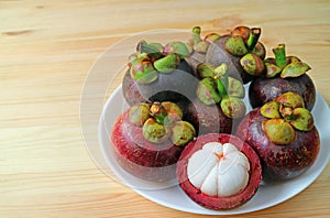 Plate of Ripe Purple Mangosteen Whole Fruits and Opened to Show Delectable Pure White Meat on the Wooden Table