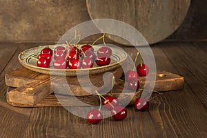 A plate of ripe red cherry berries on the rustic wooden boards background, harvesting cherries in the village