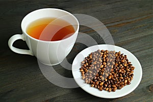 Plate of Roasted Barley with a Cup of Hot Japanese Barley Tea or Mugicha on Wooden Table