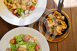 Plate with salad with meat and pan with baked potato