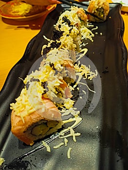 A plate of salmon skin roll sushi with cheese and black salmon roe on top