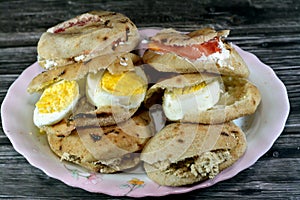 A Plate with Sandwiches of Feta white cheese with slices of tomatoes, traditional plain tahini halva or Halawa Tahiniya and slices