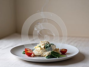 Plate of scrambled eggs with spinach and tomatoes.
