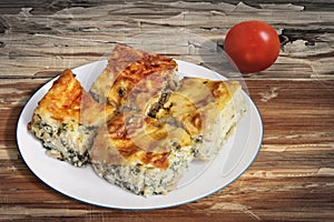 Plateful Of Serbian Traditional Cheese Spinach Pie Zeljanica Slices Set On Old Garden Table Surface With Ripe Tomato