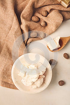 Plate with shea butter and nuts on light background