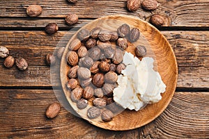 Plate with shea butter and nuts on wooden background