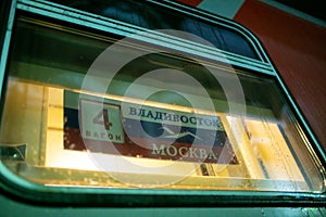 A plate showing the route of the Vladivostok-Moscow branded train behind the glass of a passenger railroad car