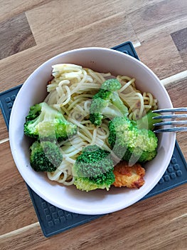 Plate with simple healthy food - spaghetti pasta, broccoli, chicken on a wooden table. Lunch or dinner in an ordinary family,