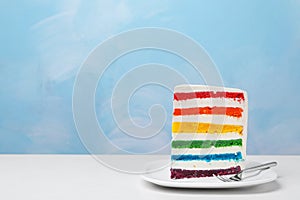Plate with slice of delicious rainbow cake