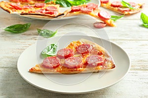 Plate with slice of tasty pizza on wooden table