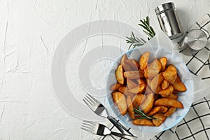 Plate of sliced baked potato wedges, salt, forks on white background, top view. Space for text