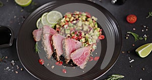 Plate with sliced grilled fried tuna steak covered with sesame seeds and traditional salsa garnish