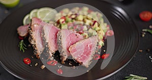 Plate with sliced grilled fried tuna steak covered with sesame seeds and traditional salsa garnish