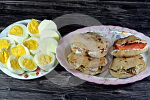 A plate of slices of boiled eggs and Sandwiches of Feta white cheese with slices of tomatoes and traditional plain tahini halva or