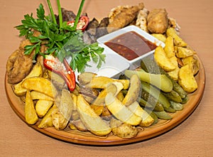 Plate with snacks, meat, potatoes, cucumber, pepper. Background