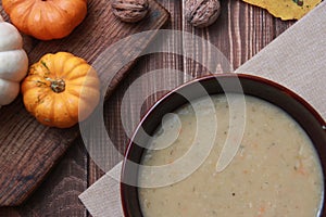 a plate of soup and mini pumpkin on a wooden table