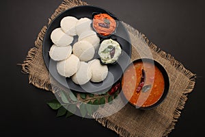 Plate of south indian food idli red chutney, coconut chutney.