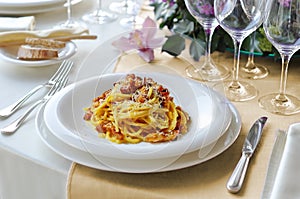 Plate with spaghetti carbonara on a laid table