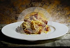 Plate with spaghetti carbonara on rough wooden table