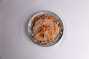 Plate of spaghetti pasta with tomato on color background