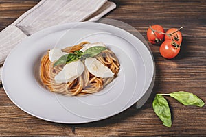 Plate of spaghetti topped with tomato, mozzarella and basil, to recreate the colors of the Italian flag