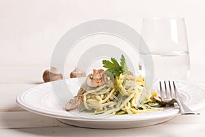 Plate of spaghetti prepared from zucchini and mushroom sauce on wooden table