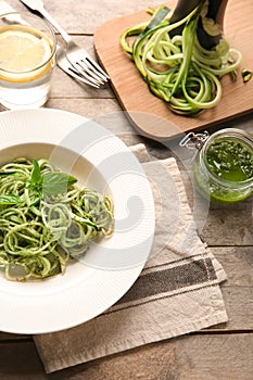 Plate of spaghetti with zucchini and pesto sauce on wooden table