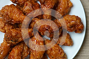 Plate of spicy deep fried chicken wings, Korean food style on wooden table