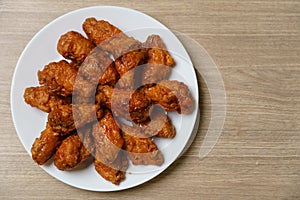Plate of spicy deep fried chicken wings, Korean food style on wooden table