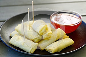 A plate of spring rolls with sweet chili dip sauce. outside restorante photo