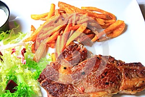Plate of steak with french fries and lettuce salad