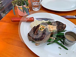 A plate of steak with mashed potatoes and green beans