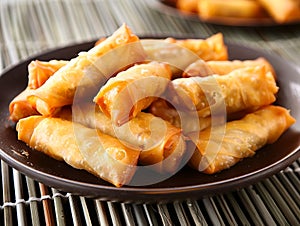 A plate of stuffed spring rolls on a bamboo mat