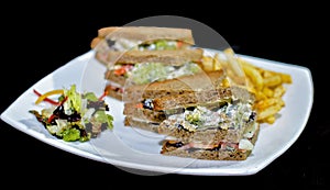 A plate of succulent, delicious looking vegetable club sandwiches ready to be eaten, served along with a homemade salad and hand c