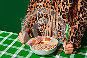 Plate of sweet cornflakes with milk, fried eggs and bacon on green tablecloth. Unordinary combination photo