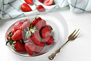 Plate with sweet ripe strawberries on white wooden table