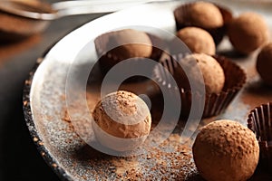 Plate with tasty chocolate truffles on grey table