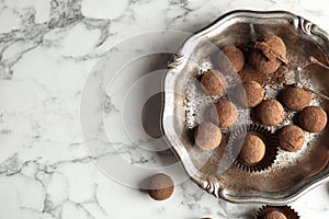 Plate of tasty chocolate truffles on marble background, top view